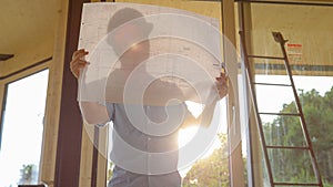 LENS FLARE: Architect looks at his floor plans for the house on a sunny day.