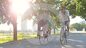 LENS FLARE: Cheerful blonde woman and her boyfriend riding bikes around the park