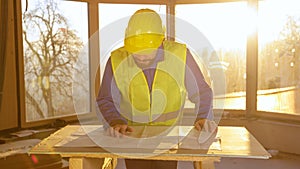 LENS FLARE: Construction site manager looks at the floor plans at sunrise.