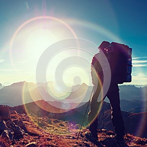 Lens flare defect. Tourist guide on trekking path with poles and backpack. Experienced hiker