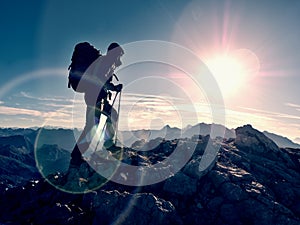 Lens flare defect. Tourist guide on trekking path with poles and backpack. Experienced hiker