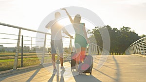 LENS FLARE: Happy woman walking to airport with boyfriend outstretches her arm.