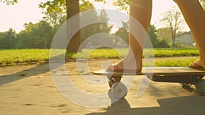 LENS FLARE: Sporty girl in flip flops skating in the park on sunny spring day.