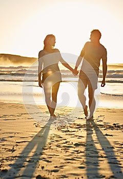 Lens flare, sunset and couple holding hands at beach, ocean and sea with affection, bonding and love. People, partners