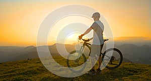 LENS FLARE: Young male tourist observes the landscape before mountain biking