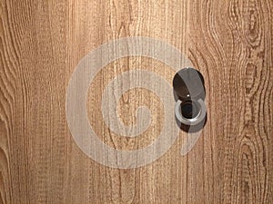 Lens peephole on new wooden door close up