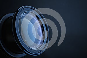 Lens of professional camera on dark blue background, closeup