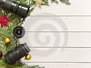 Lenses for reflex camera and Christmas decorations on a white wood background