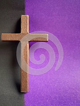 Lent Season, Holy Week, Good Friday, Easter Sunday Concept. Close up of wooden cross with black and purple colours background.