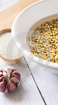 Lentil bowl with water next to onion and garlic