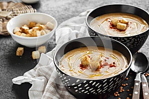 Lentil cream soup with paprika and crouton in black ceramic bowls