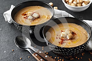 Lentil cream soup with paprika and crouton in black ceramic bowls