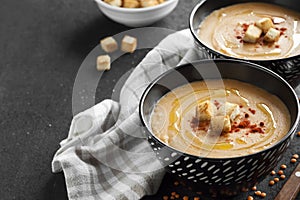 Lentil cream soup with paprika and crouton in black ceramic bowls