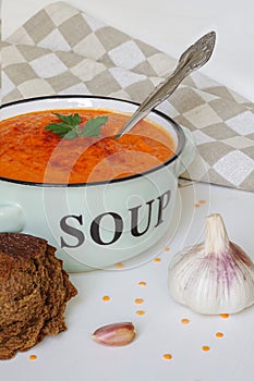 Lentil cream soup in a rustic bowl with piece of black bread