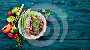 Lentil with radish, cherry tomatoes, beans and vegetables. Healthy food. On a blue wooden table.