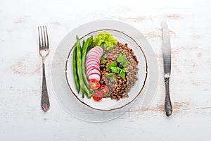 Lentil with radish, cherry tomatoes, beans and vegetables. Healthy food. On a white wooden table.