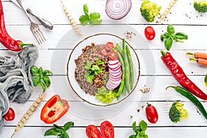 Lentil with radish, cherry tomatoes, beans and vegetables. Healthy food. On a white wooden table.