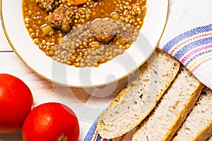 Lentil soup with fricandel, tomatoes and bread