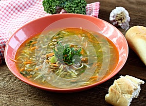 Lentil soup with lots of vegetable, parsley on the top and baguette.