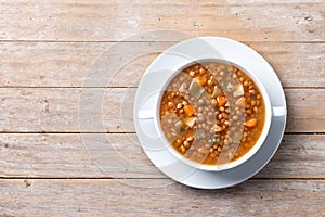 Lentil soup with vegetables in bowl on wooden table