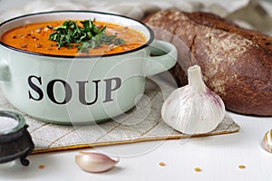 Lentil tomato cream soup in a rustic bowl with loaf of black br