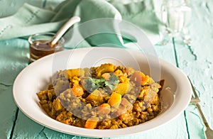 Lentil and vegetable curry in bowl on rustic blue table with chutney in background - selective focus image