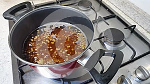 Lentils boiling in a red cooking pot. Cooking in the kitchen.