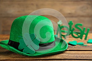 Leprechaun hat, decorative clover leaf and party glasses on wooden background. St Patrick`s Day celebration