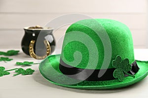 Leprechaun hat, decorative clover leaves and pot of gold on white wooden table, closeup. St Patrick`s Day celebration