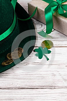 Leprechaun hat, gold coins, clover shamrock and gift with green ribbon on white background. Good luck symbols for St