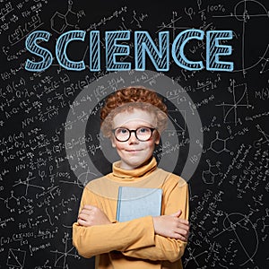 Lern Science. Clever student child on blackboard background with maths formulas photo