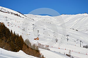 Les Sybelles ski domain in France - view of long chair lifts and pistes, on a blue sky day