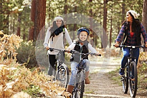 Lesbian couple cycling in a forest with their daughter