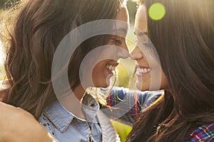 Lesbian couple embrace touching noses, eyes closed, close up