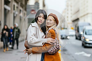 Lesbian couple hugging each other while standing on the street.