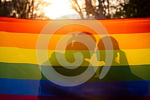 Lesbian couple hugging outdoors. LGBT rainbow flag.