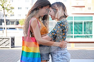 Lesbian couple hugging and smiling at street.