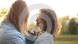 Lesbian couple kissing in the autumn park at a meeting. The kid in the arms of one of the women repels the other