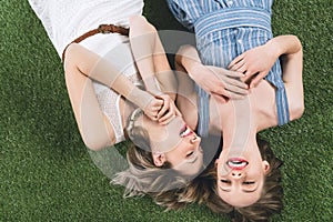 Lesbian couple laughing while lying together on the grass