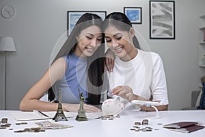 Lesbian couple plans to save money for a trip around the world. Travel budget concept, passport, monument model and aircraft toy