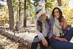 Lesbian couple sitting in a forest, looking at each other