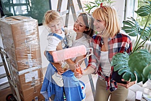 Lesbian parents with boxes - couple moving into a new home with a toddler girl