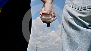 Lesbians hold hands close up on the sky background