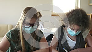 Lesson in the classroom in high school. Masked children in the classroom, write a test paper. Post-quarantine life, back