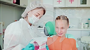 lesson in dental clinic for school girl, dentist woman teaching teen girl how to brush teeth