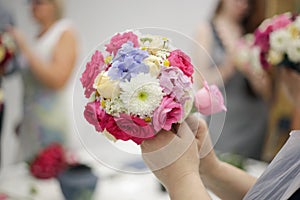 lesson on making a wedding bouquet in the shape of a ball. A young woman makes a bouquet of freshly cut bright flowers.