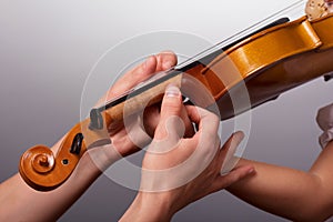 The lesson of playing the violin. Teacher helps to hold the violin