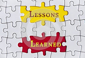 Lessons learned text on Jigsaw Puzzle with yellow and red background. Improvement concept