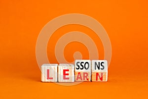 Lessons to learn symbol. Concept word Lessons learn on wooden cubes. Beautiful orange table orange background. Business education