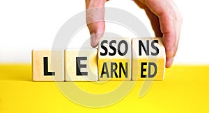 Lessons to learn symbol. Concept word Lessons learn on wooden cubes. Beautiful yellow table white background. Businessman hand.